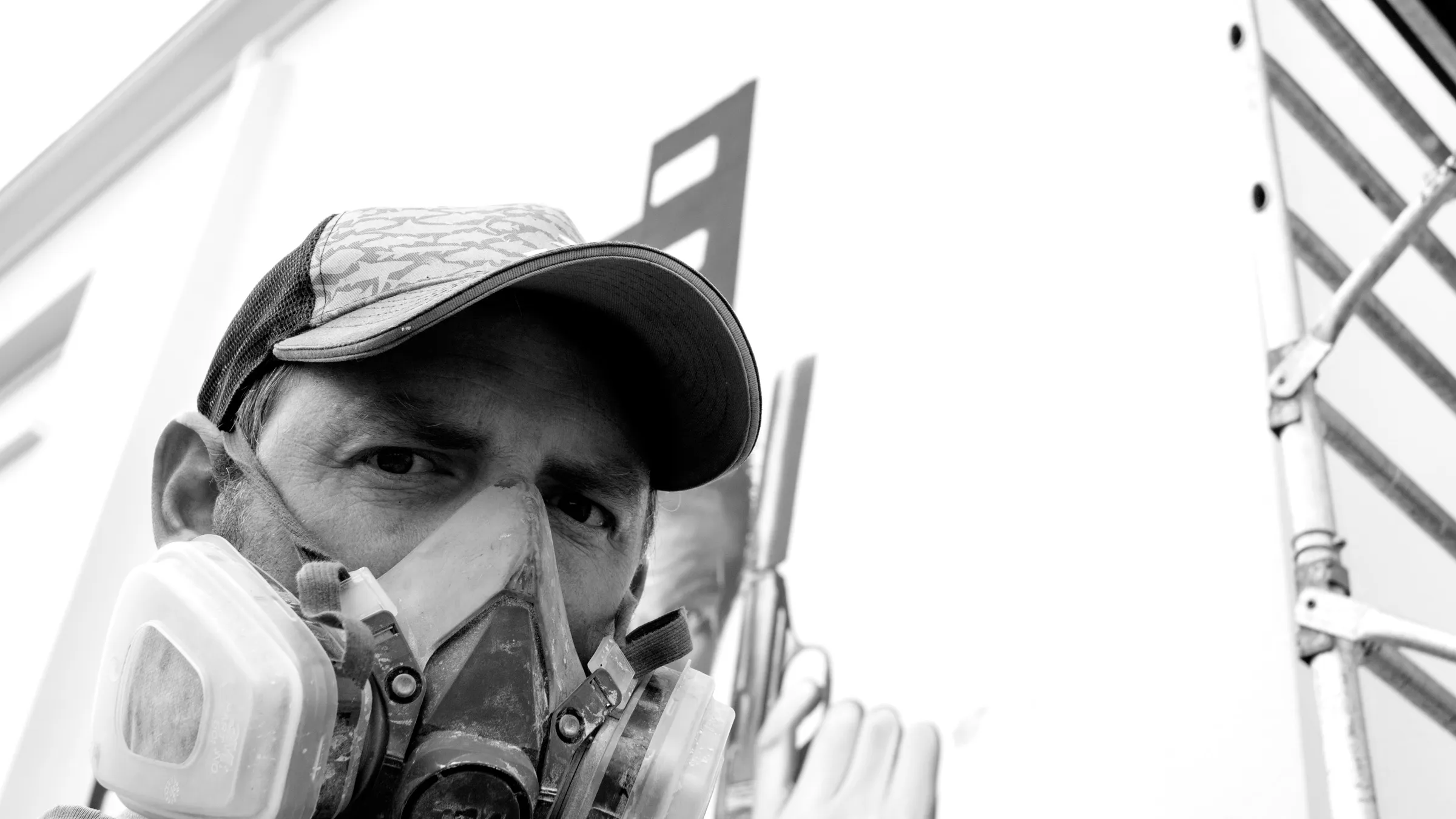 Portrait de Gwendal Larher, artiste peintre muraliste installé à Morlaix, en Bretagne, avec masque de protection sur un chantier de fresque.