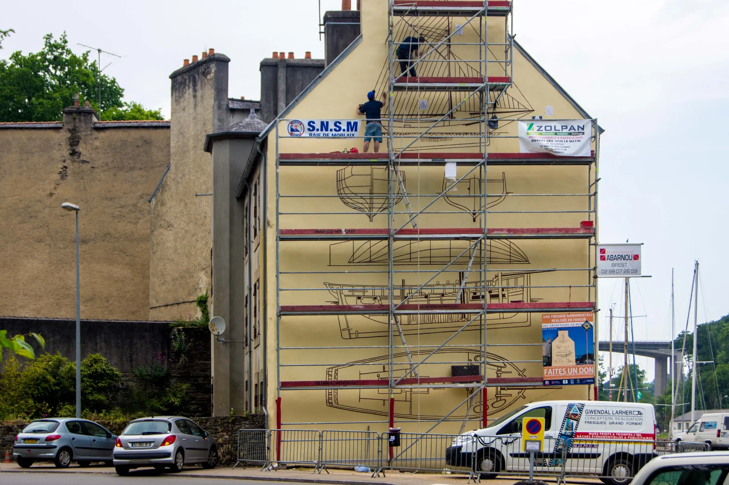 Fresque monumentale pour la SNSM peinte sur échafaudage, plan de voilier à l'échelle d'un pignon