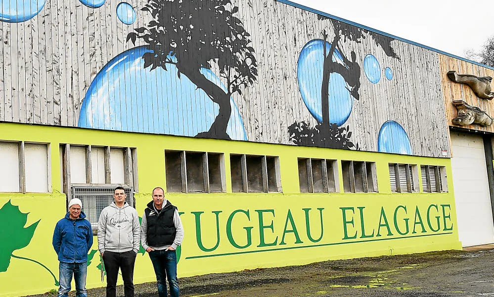 Photo de presse d'une fresque peinte par Gwendal Larher sur le bâtiment de l'entreprise Rugeau Élagage, avec trois hommes posant devant.