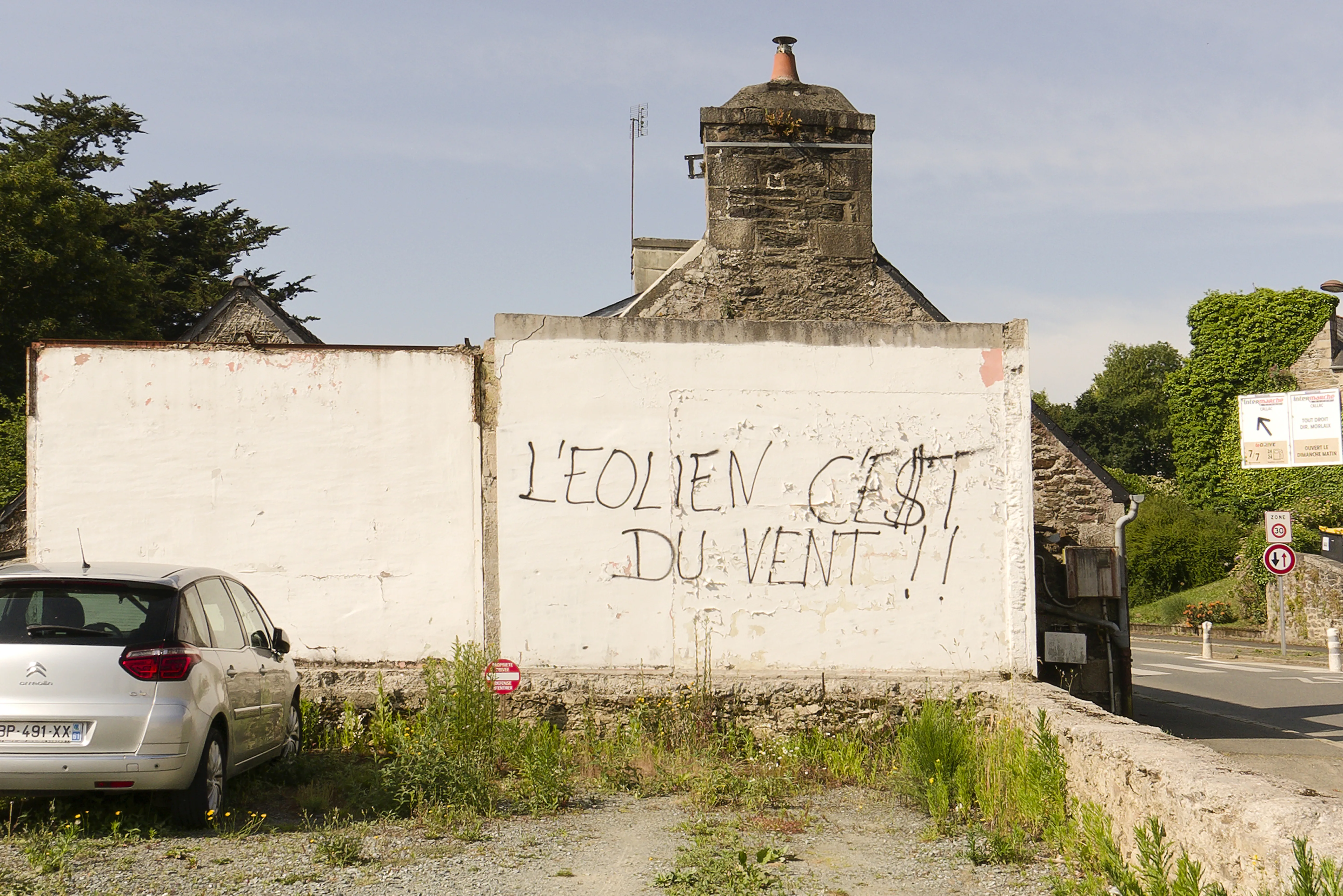 Mur d'entrée de ville dégradé par des graffitis, avant la fresque trompe-l'œil à Callac