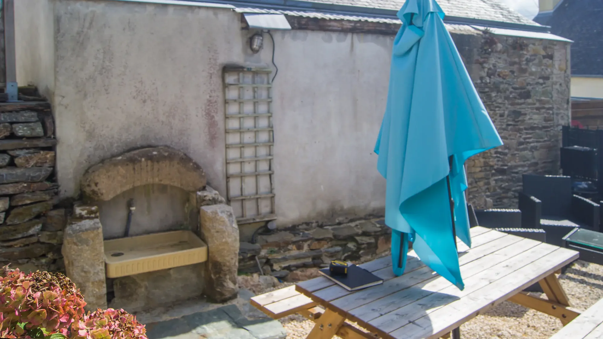 Avant, cour d'une location touristique à Plestin-les-Grèves, enduit gris, lavoir en granit, table de pique-nique