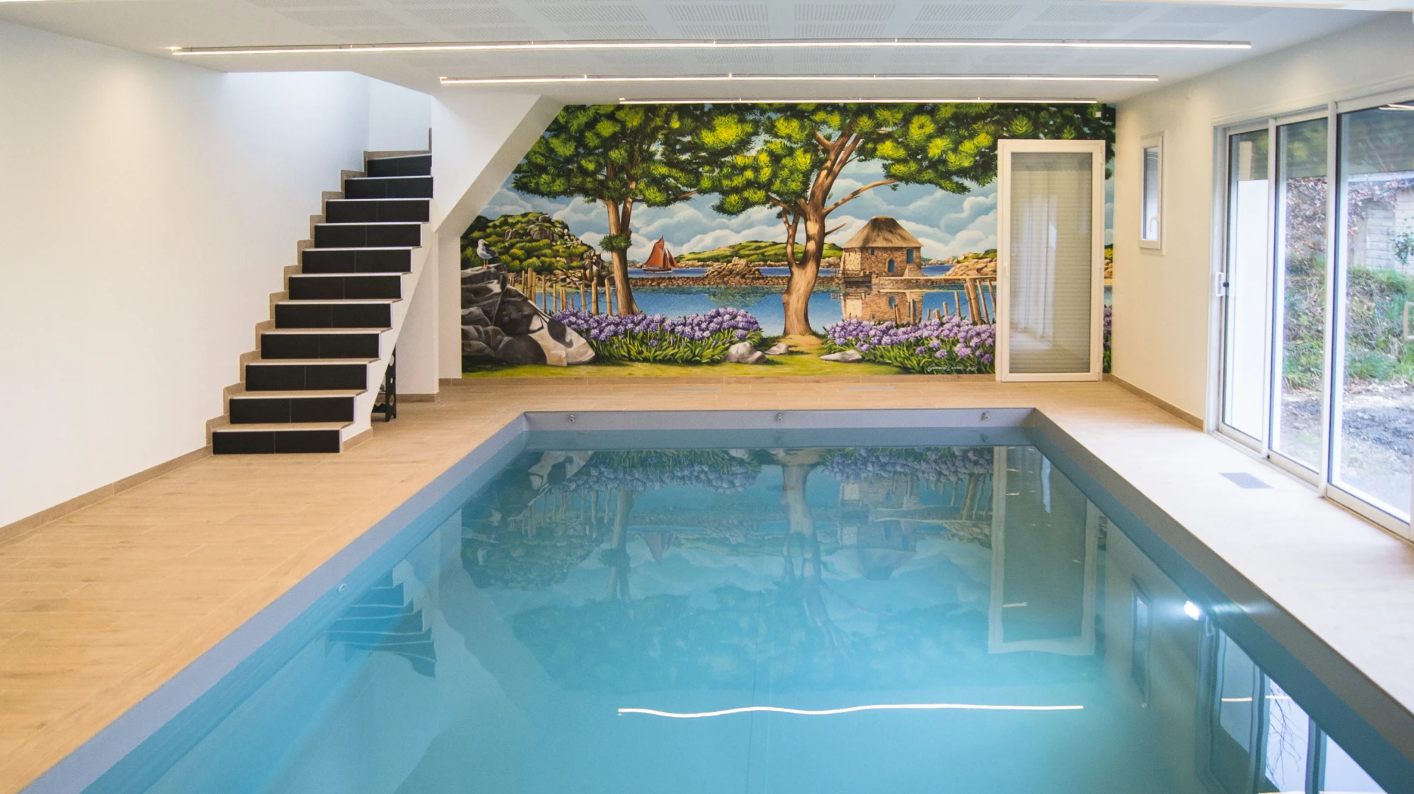 Piscine intérieure à Paimpol après réalisation : moulin à marée et voilier en trompe-l'œil, décor immersif résistant à l'humidité